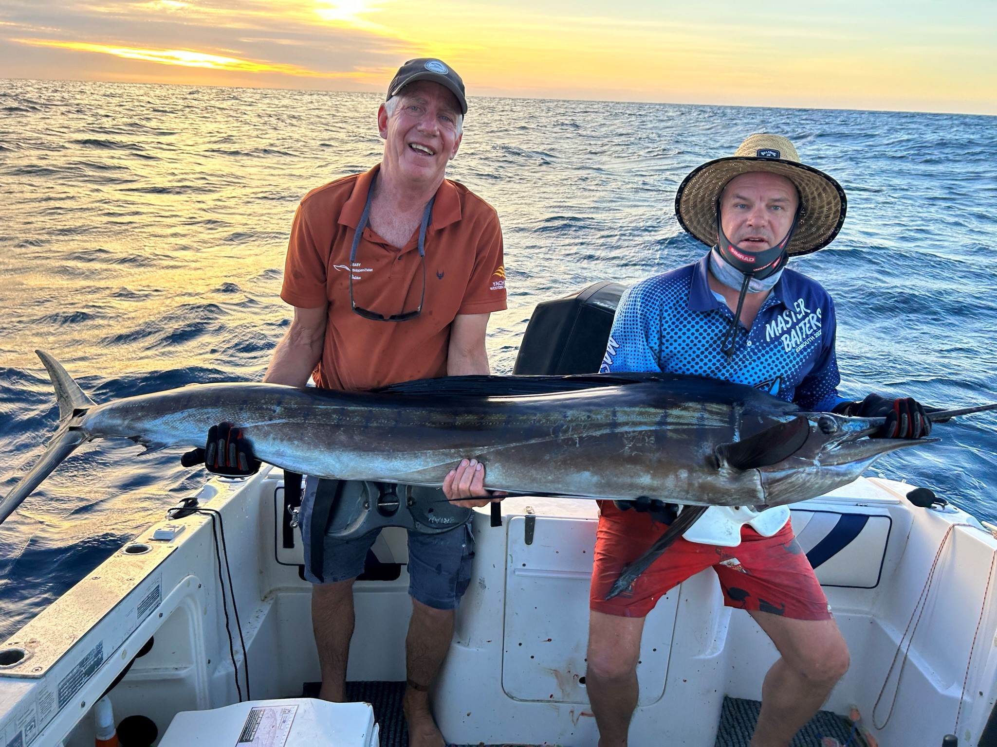 Two men holding large marlin freshly caught on fishing trip.