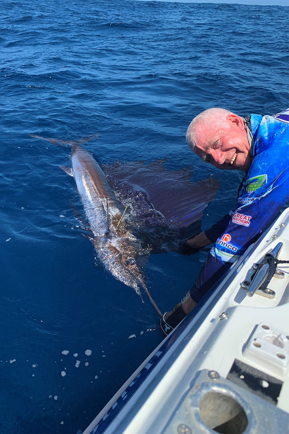 Brian Edwards leaning over boat to land a huge sailfish off the coast of Western Australia
